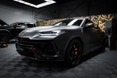 Bir mat siyah Lamborghini Urus Performante kapalı bir yerde, keskin çizgileri, sarı fren kalibreleri ve siyah alaşımlı tekerlekleri sergiliyor..