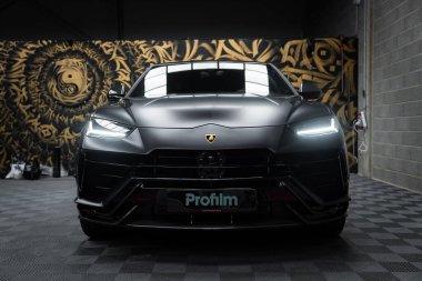 Bir Lamborghini Urus Performansı, arka planda altın ve siyah bir duvar resmiyle kapalı bir yerde sergilenir..