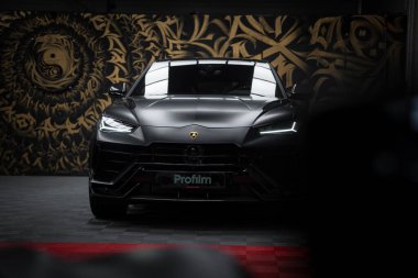 Lamborghini Urus Performante 'nin siyah kaplamalı yakın plan görüntüsü, kapalı bir galeride ya da stüdyoda altın ve siyah soyut eserlere karşı..