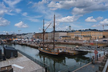 View of Helsinki's city center featuring a historic sailing ship in the harbor, the iconic Helsinki Cathedral, and classic European style buildings along the waterfront. clipart