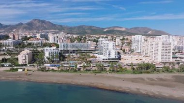 İspanya 'nın Benalmadena kentinin havadan görünüşü. Sahilde yüksek binalar, yemyeşil alanlar ve piramit şeklindeki Sierra de Mijas..