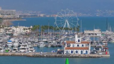 Uzakta Sierra de Mijas ile Benalmadena 'nın yat, yüksek binalar, palmiye ağaçları ve Akdeniz' in havadan görüntüsü.