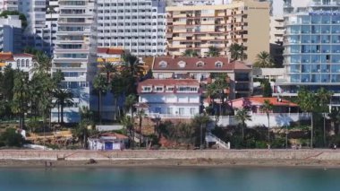 Benalmadena, İspanya 'nın havadan görünüşü, yüksek binalar, kırmızı çatılı bir villa, yemyeşil ve palmiye çizgili sahil geçidi.