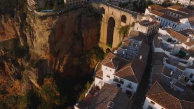 İspanya 'nın Ronda kentinin havadan görünüşü Puente Nuevo köprüsünün altını çiziyor, binaları beyazlatıyor ve altın bir günbatımının altında tepeleri yuvarlıyor..