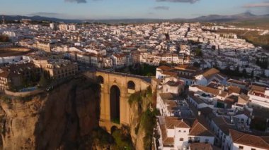 Ronda 'nın Puente Nuevo köprüsü şehrin parçalarını birbirine bağlayan derin bir vadiyi kapsıyor. Beyazlatılmış binalar ve yuvarlanan tepeler gün batımında görülebilir..