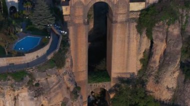 Ronda 'nın Puente Nuevo köprüsü, beyazlatılmış binalar ve yuvarlanan tepelerle çevrili, günbatımının sıcacık parıltısıyla aydınlanan derin bir vadiyi kaplar..