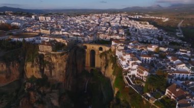 Ronda 'nın dramatik uçurumları ve Puente Nuevo köprüsü gün batımında aydınlanıyor, beyazlatılmış binalar ve El Tajo geçidi sergileniyor..