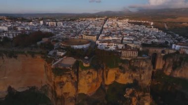 Güneş batarken Ronda, İspanya 'nın havadan görünüşü Plaza de Toros, beyaz binalar ve sıcak bir gökyüzünün altındaki uzak dağlar..