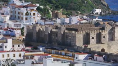 Tarifa 'nın ortaçağ kalesi Castillo de Guzman el Bueno' nun havadan görünüşü, Cebelitarık Boğazı ve Fas 'ın parlak mavi suları boyunca uzanan ana hatlarıyla..