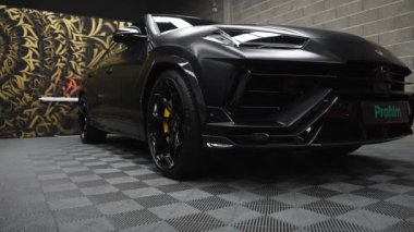 Lamborghini Urus, altın ve siyah desenli bir duvara dayanan ve lüks tasarımını ön plana çıkaran, iç mekanda siyah bir kaplamayla sergileniyor..