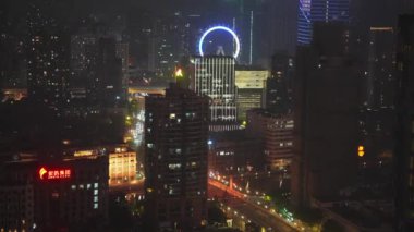 Şangay 'da canlı bir gece sahnesi. Büyük bir dönme dolabı, hareketli bir trafik ve binaların üzerindeki renkli ışıklar şehrin hayat dolu gece hayatını aydınlatıyor..