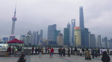Şangay 'ın hareketli Bund manzarası. Doğu İnci Kulesi, Şangay Kulesi ve küçük bir polis aracı ve kırmızı şemsiyeli canlı bir gezinti alanı..