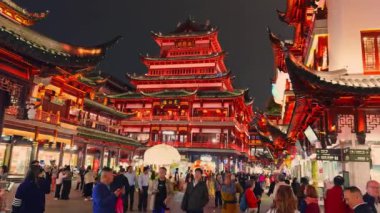 Şangay 'daki Yu Gardens kırmızı ve altın ışıklarla aydınlanıyor. Geleneksel mimari ve coşkulu kalabalıkları şenlikli bir atmosferde sergiliyor..