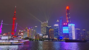 Shanghai 'nin ışıl ışıl parlayan gece silueti aydınlatılmış Doğu İnci Kulesi, Huangpu Nehri' nde bir yolcu gemisi ve renkli gökdelenler içerir..
