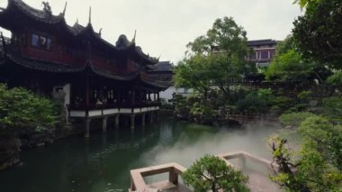 Şangay 'daki Yu Gardens' ta karmaşık ahşap yapılar, ters dönmüş saçaklar, yemyeşil yeşillikler ve sakin bir gölet, somut klasik bahçe tasarımı yer alıyor..