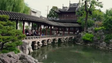 Şangay 'daki Yu Gardens' ta geleneksel pavyonlar, bir taş köprü, yeşillik ve doğal ve mimari elementlerin bir karışımını sergileyen koi balığı bulunuyor..