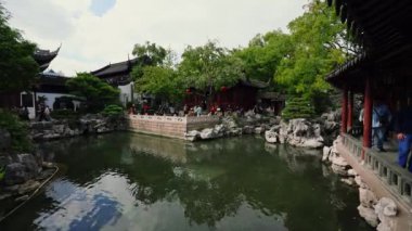 Ziyaretçiler Şangay 'daki Yu Gardens' ı keşfediyor. Geleneksel mimari, yemyeşil alanlar ve çevreyi yansıtan sakin bir gölet bulunuyor..