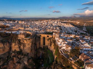 Ronda, İspanya gün batımında Puente Nuevo köprüsü derin bir vadiye yayılırken yukarıdan görülmektedir. Beyazlaşmış binalar ve uçurumlar altın ışıkla yıkanır..