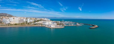 Benalmadena, İspanya 'nın havadan çekilmiş bir görüntüsünde, tekneleri, kumlu plajları, yüksek binaları, dönme dolabı ve dağları olan bir marina görülüyor..