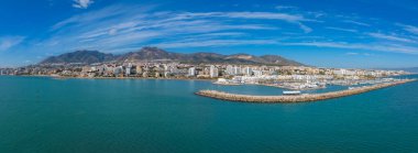 İspanya 'nın Benalmadena kentinin havadan görünüşü, açık mavi gökyüzünün altında kayıkları, beyaz ve pastel binaları ve dağları olan bir marinaya ev sahipliği yapıyor..