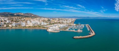 Görüntü, Benalmadena 'nın marinasını kayıklar, yüksek binalar ve dönme dolapla yakalıyor. Sahil ve deniz ufka kadar uzanıyor..
