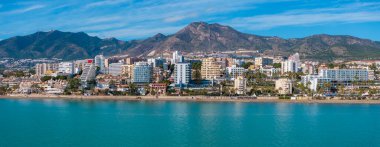 Turkuaz deniz, kumlu plaj, palmiye ağaçları, modern ve geleneksel mimari ve Sierra de Mijas 'ın yer aldığı Benalmadena, İspanya' nın hava perspektifi.