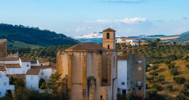 İspanya 'daki Setenil de las Bodegas' da kayalık arazide yuva yapmış, tarihi bir kilise kulesi ve uzak tepe kasabası manzaralı, bembeyaz binalar yer almaktadır..