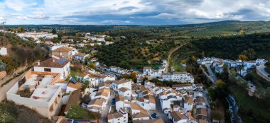 Resim Setenil de las Bodegas 'ı yukarıdan yakalıyor, kayaların tepelerine ve zeytinliklerle çevrili beyazlatılmış evleri vurguluyor..