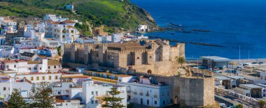 Tarifa, İspanya 'da tarihi Castillo de Guzman el Bueno, beyazlatılmış binalar, kayalık kıyı şeridi ve Akdeniz' e karşı yemyeşil tepeler yer alıyor..