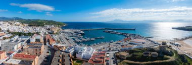 Tarifa 'nın beyazlatılmış binaları, hareketli limanları ve tarihi şatosu yukarıdan görülüyor. Kıyı şeridinde kumlu plajlar ve uzak dağlar var..