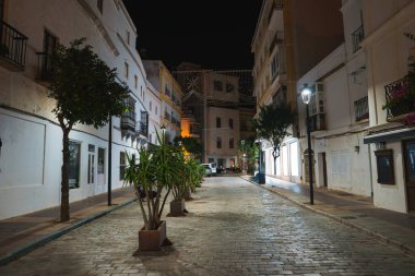 İspanya 'nın Tarifa kentindeki dar bir kaldırım taşı caddesi geceleri aydınlanıyor. Yol boyunca balkonları olan, saksı bitkileriyle süslenmiş, bembeyaz binalar..