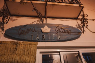 Tarifa, İspanya 'da bir binada' Anima Gitana 've' Tarifa 'yazılı bir sörf tahtası. Kağıt tekne tasarımı ve Akdeniz mimarisi özellikleri.