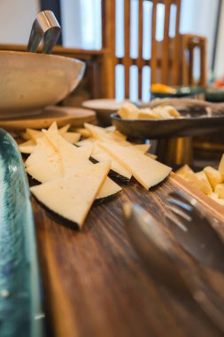 Marakeş 'teki lüks bir butik otel ortamını yansıtan, seramik ve ahşap tabaklarla çevrili ahşap bir tahtanın üzerinde dilimlenmiş peynirin gurme gösterisi..