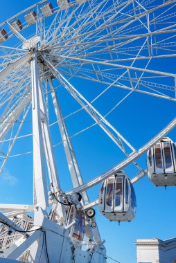 Kapalı gondolları olan modern beyaz bir dönme dolap açık mavi gökyüzüne karşı San Francisco 'da güneşli bir havada dimdik ayakta duruyor..