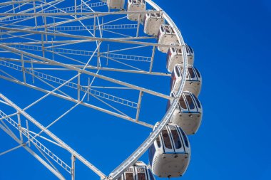 San Francisco 'daki bir dönme dolabın detaylı bir görüntüsü. Metal iskeletini ve açık mavi gökyüzüne karşı kapalı kulübelerini gösteriyor..