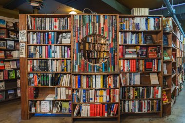 Los Angeles 'taki The Last Bookstore' daki canlı bir kitaplık dairesel bir kesit içeriyor ve bir tünel etkisi yaratıyor. Ilık ışıklandırma ve ahşap raflar atmosfere eklenir.