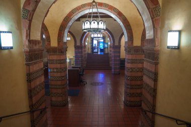 The image shows a historic building interior at UCLA, featuring ornate arches, intricate tile work, terracotta flooring, and a large chandelier. clipart