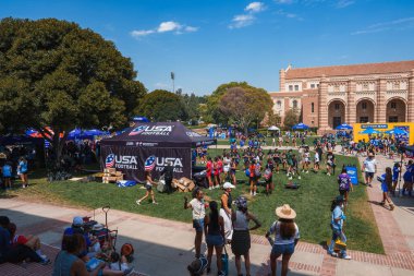 UCLA 'nın tarihi binalarla çevrili otlak kampüsünde büyük bir kalabalık toplanıyor. Bir Amerikan futbol çadırı ve çeşitli kabinler şenlikli bir atmosfer yaratır..