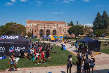 UCLA 'nın kampüsündeki canlı bir toplantıda arka planda Royce Hall' un olduğu çimenli bir alanda bir kalabalık yer alıyor. ABD Futbol Çadırları bir spor etkinliği öneriyor.