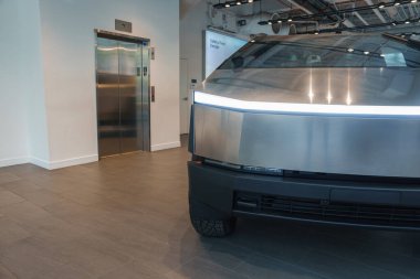 Açısal tasarımı ve metalik kaplamasına sahip fütüristik bir araç kapalı mekanda sergilenmektedir. Döşemede döşeme ve asansör var. Bu da bir galeri olduğunu gösteriyor..