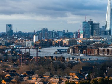 Thames Nehri, Çömlek Gökdeleni ve Kanarya Rıhtımı ile Londra 'nın havadan görünüşü. Parçalı bulutlu gökyüzünün altındaki yerleşim ve sanayi binaları.