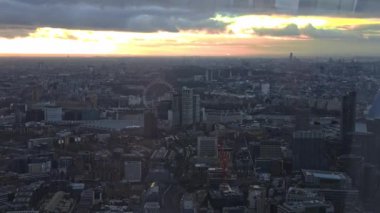 London Eye, Thames River ve dramatik bulutlar altında modern ve tarihi mimarinin bir karışımı ile gün batımında gökyüzü..