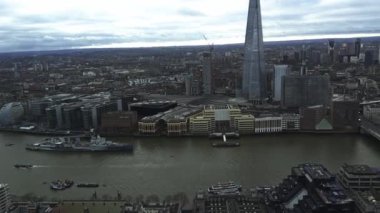 The Shard, River Thames ve London Bridge ile panoramik bir manzara. Ufuk çizgisi bulutlu bir gökyüzü altında modern ve tarihi mimariyi harmanlıyor..