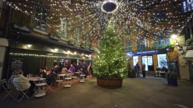 Neal 's Yard, Londra' da coşkulu bir sahne. Büyük bir Noel ağacı, yanıp sönen ışıklar ve tatil atmosferinin tadını çıkaran insanlar..
