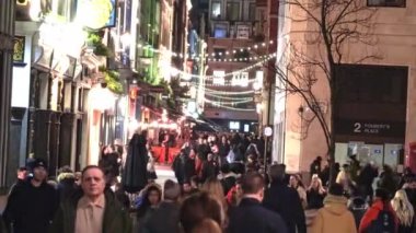 Londra 'daki Foubert' s Place 'de canlı bir sokak sahnesi, Noel atmosferinin keyfini çıkaran kalabalıkla birlikte neşeli ışıklar ve dekorasyonlar..