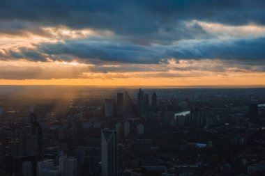 Londra silueti, Çömlek ve diğer gökdelenlerin yer aldığı dramatik bir günbatımı gökyüzüne karşı siluetlendi. Güneş ışınları bulutları deler, sıcak bir parıltı bırakır..