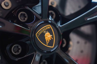 A detailed view of a Lamborghini Revuelto wheel, featuring the iconic golden bull emblem on a glossy black background, with polished spokes and lug nuts. clipart