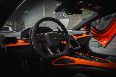 Görüntü Lamborghini Revuelto 'nun içini, siyah ve turuncu bir dizaynla yakalıyor. Direksiyon logoyu canlı turuncu bir dış görünüşle gösterir..