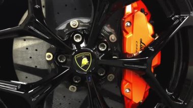 Lamborghini Revuelto 'nun logosu ve yüksek performanslı frenleriyle siyah alaşımlı tekerleğinin ayrıntılı görüntüsü. Sarı gövde ve Alman yapımı bileşenler görünür.