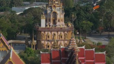 Wat Chalong 'un Phuket, Tayland' daki havadan görünüşü, süslü kuleleri, altın detayları, merkezi tapınak ve yemyeşil çevresiyle sergileniyor..